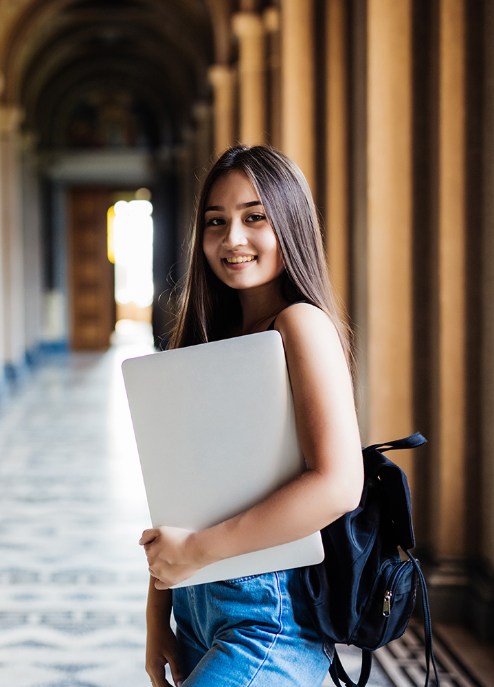 Two students with course folders outside a campus building